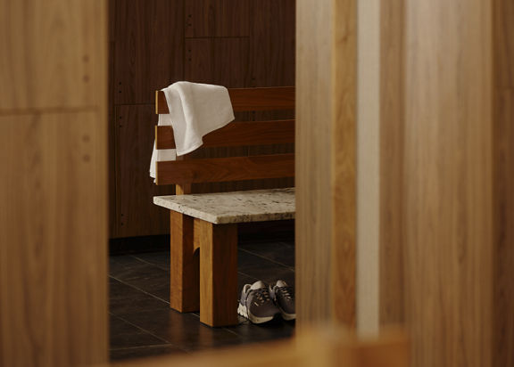A towel and tennis shoes on a bench next to a bay of lockers in the Life Time Atlantic Avenue club location.