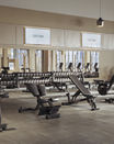 A clean and organized fitness floor with digital signage screens overhead showcasing a Life Time logo