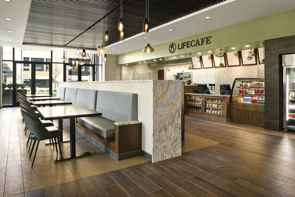 A gleaming wooden floor, tables with booths and chairs and the service counter in the LifeCafe at Life Time Ardmore