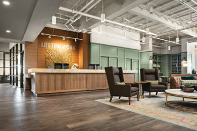 The front desk area at Life Time Work Ardmore with cushioned lounge chairs and a coffee table