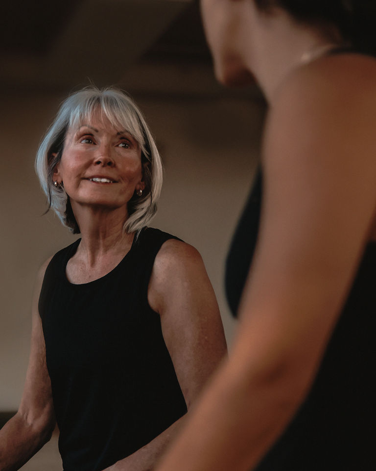 A woman talking to an instructor in her pilates class