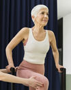 Beautiful senior woman having pilates class on performer machine with instructor