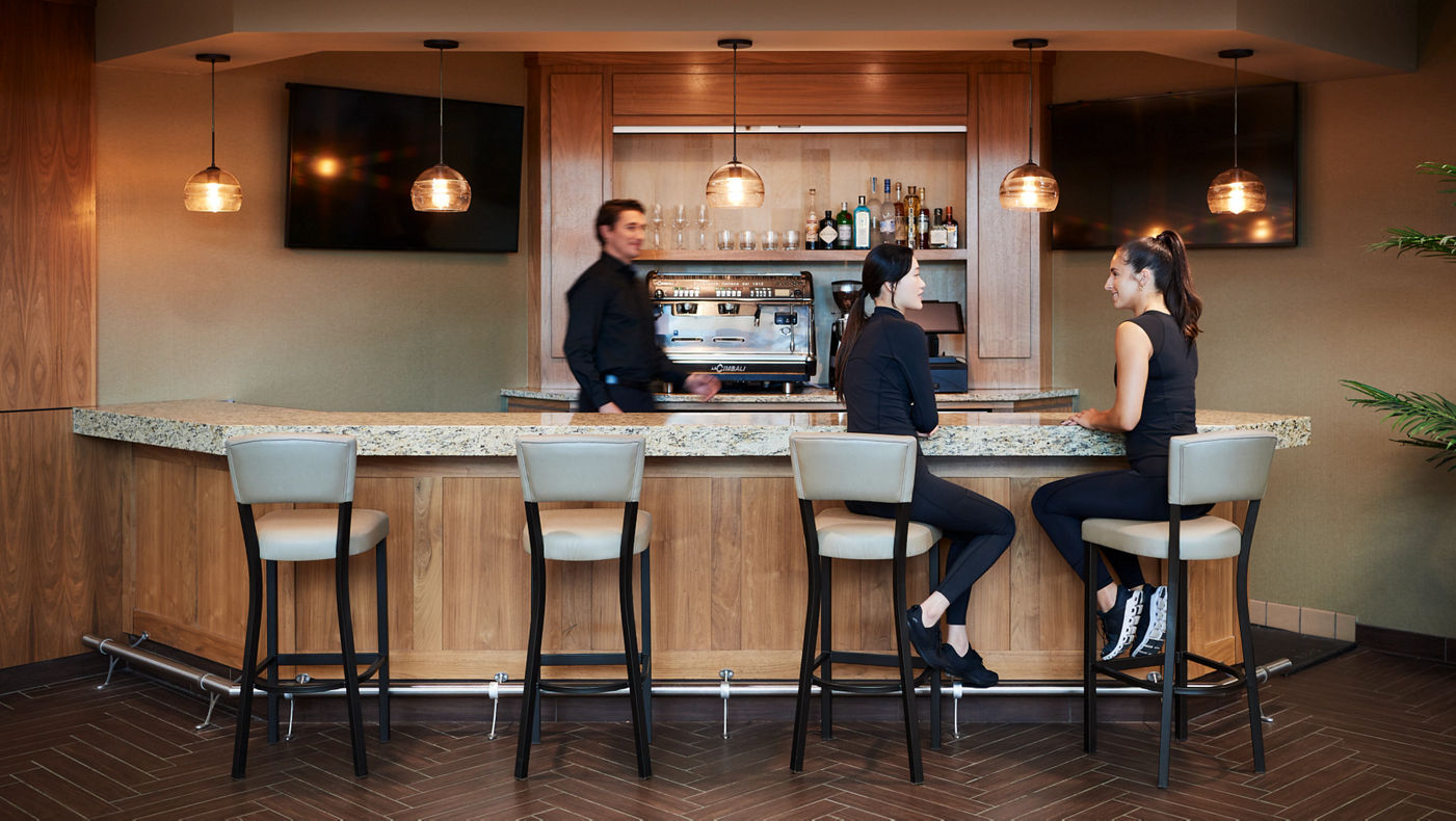 2 femals talk while sitting at a coffee bar