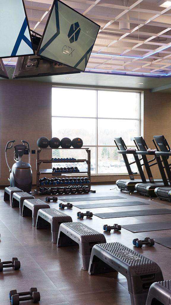 Treadmills, dumbbells and yoga mats laid out in a workout area