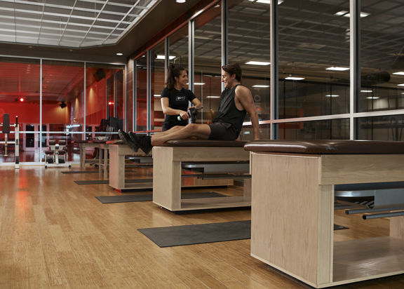 A female Dynamic Personal Trainer using a Hyperice device on a members thigh muscle