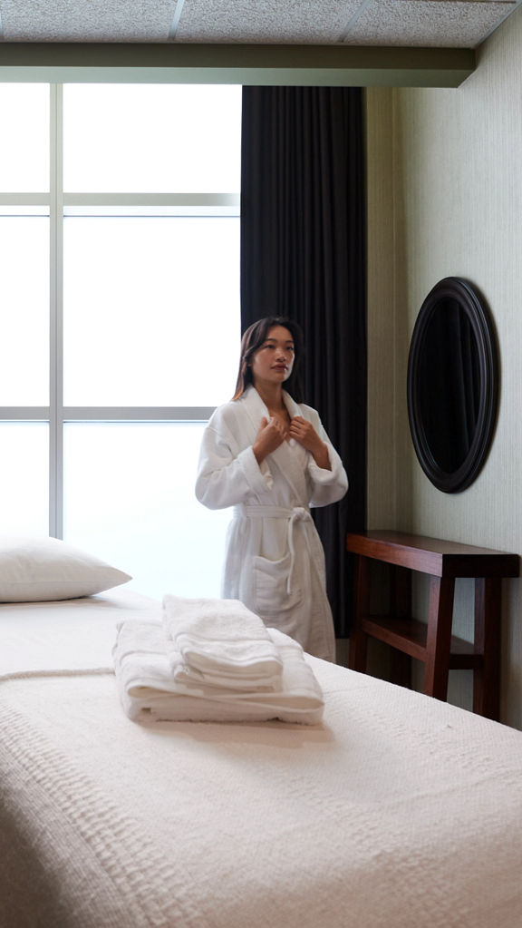 A female wearing a white robe standing next to a massage table