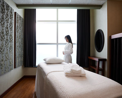 A female wearing a white robe standing next to a massage table