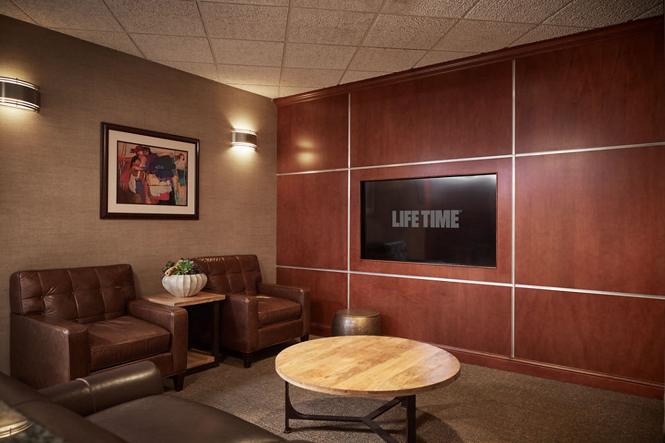 Seating area with television in a locker room at Life Time