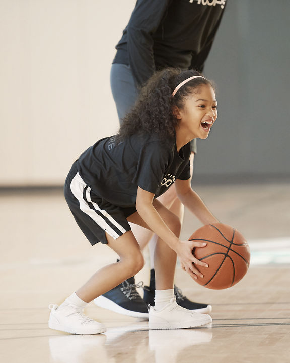 Girl holding a basketball laughing on the court.