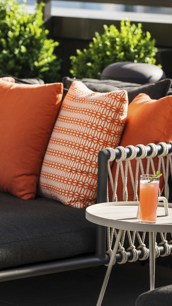 a colorful drink on a small table next to a poolside lounger