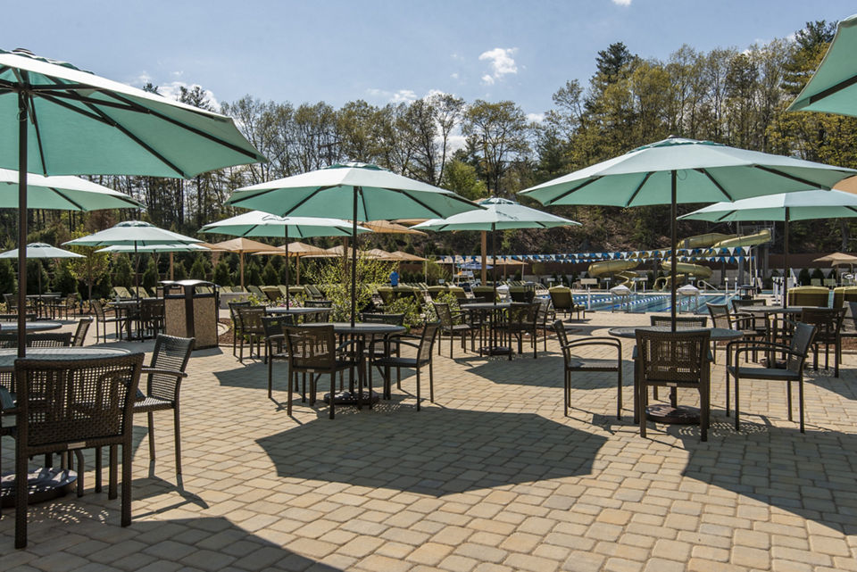 Tables, chairs, and umbrellas next to an outdoor pool