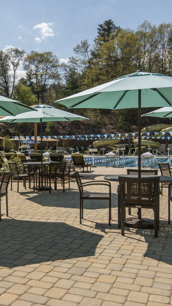 Tables, chairs, and umbrellas next to an outdoor pool