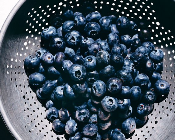 Overhead view of a metal strainer filled with fresh blueberries
