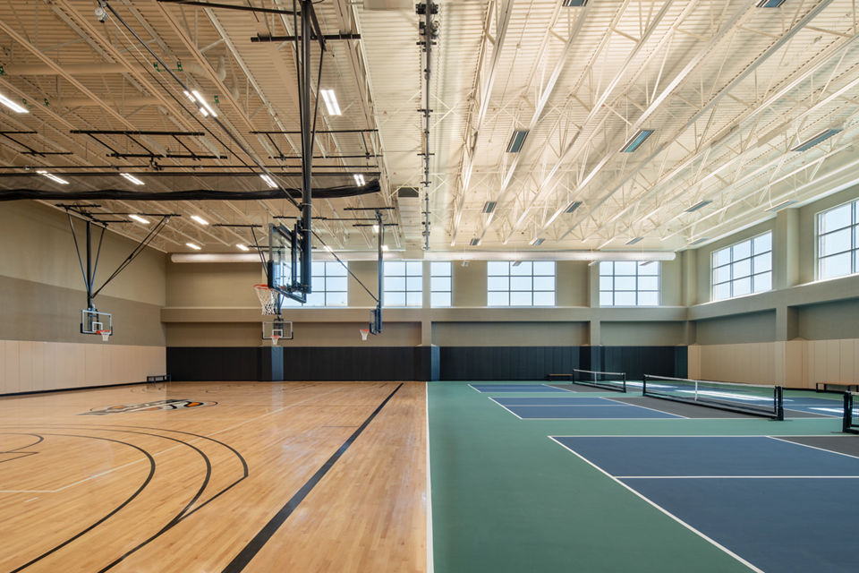 A gymnasium with a basketball court to the left and pickleball courts to the right
