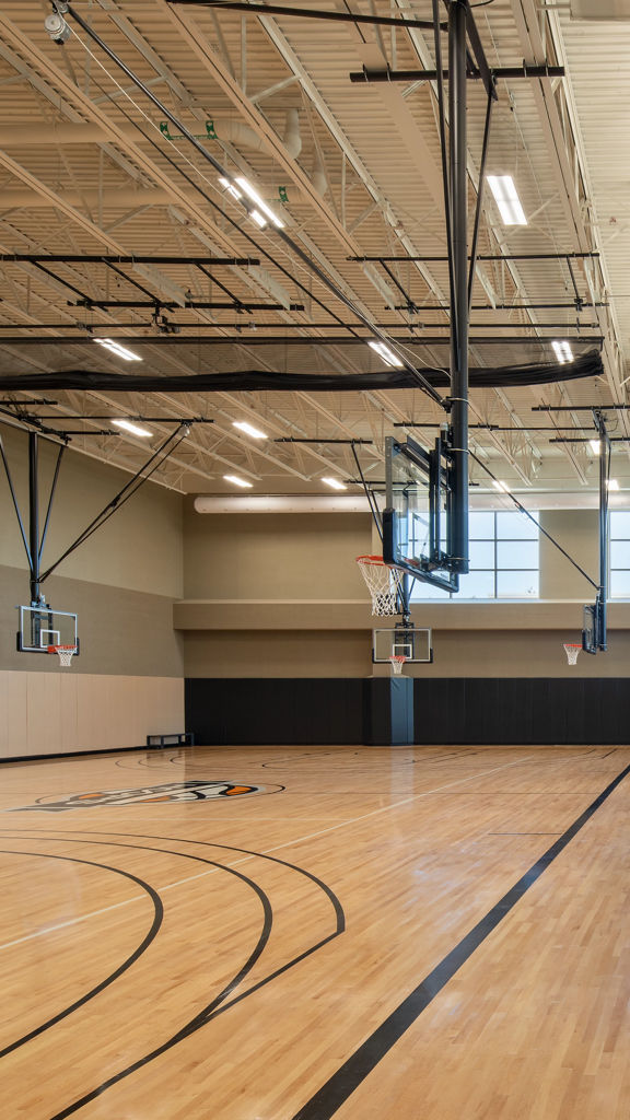 A gymnasium with a basketball court to the left and pickleball courts to the right