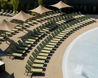 Pool lounge chairs lined up next to a zero-depth entry pool