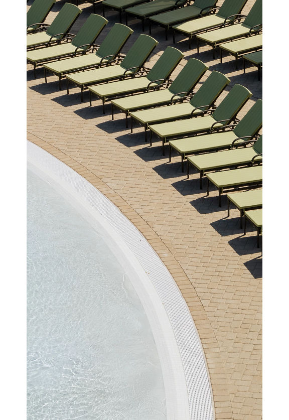 Pool lounge chairs lined up next to a zero-depth entry pool