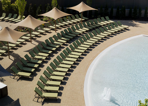 Pool lounge chairs lined up next to a zero-depth entry pool