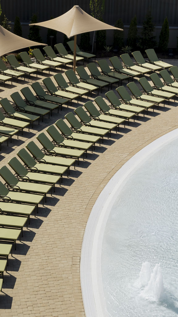 Pool lounge chairs lined up next to a zero-depth entry pool