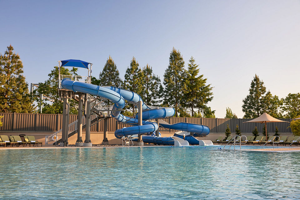 Blue Waterslides and lounge chairs at an outdoor pool.