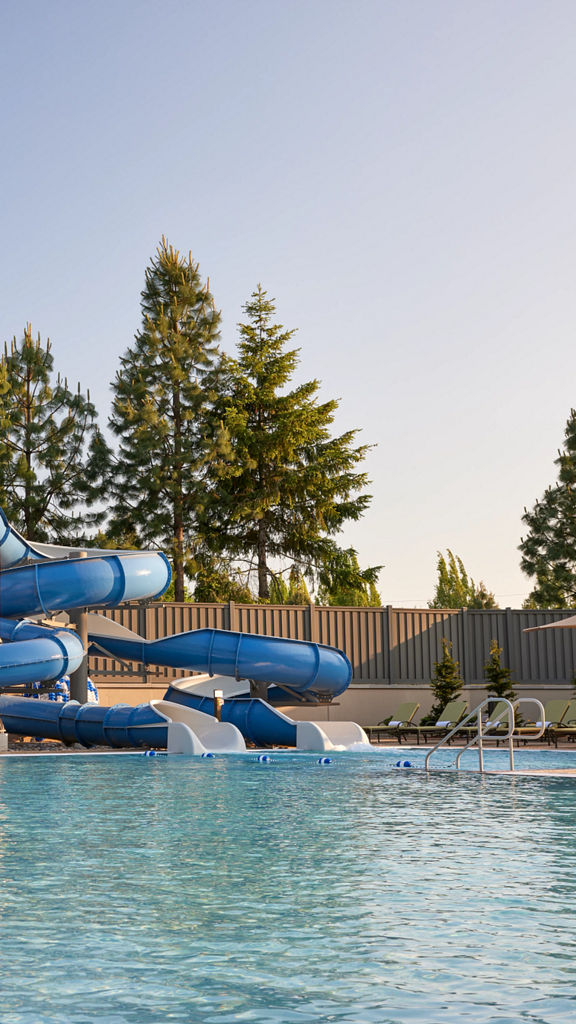 Blue Waterslides and lounge chairs at an outdoor pool.
