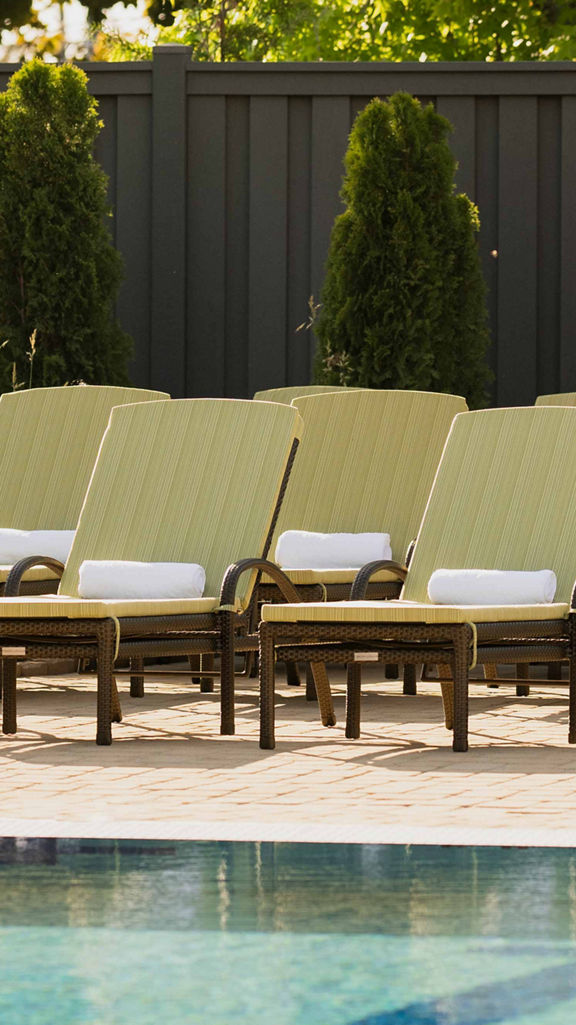 Pool lounge chairs uniformly placed next to an outdoor swimming pool