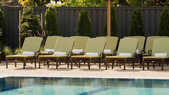 Pool lounge chairs uniformly placed next to an outdoor swimming pool