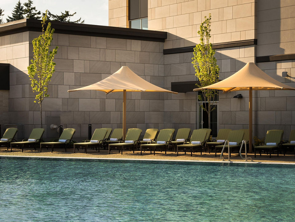 Pool lounge chairs uniformly placed next to an outdoor swimming pool