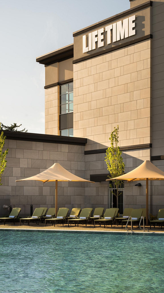 Pool lounge chairs uniformly placed next to an outdoor swimming pool