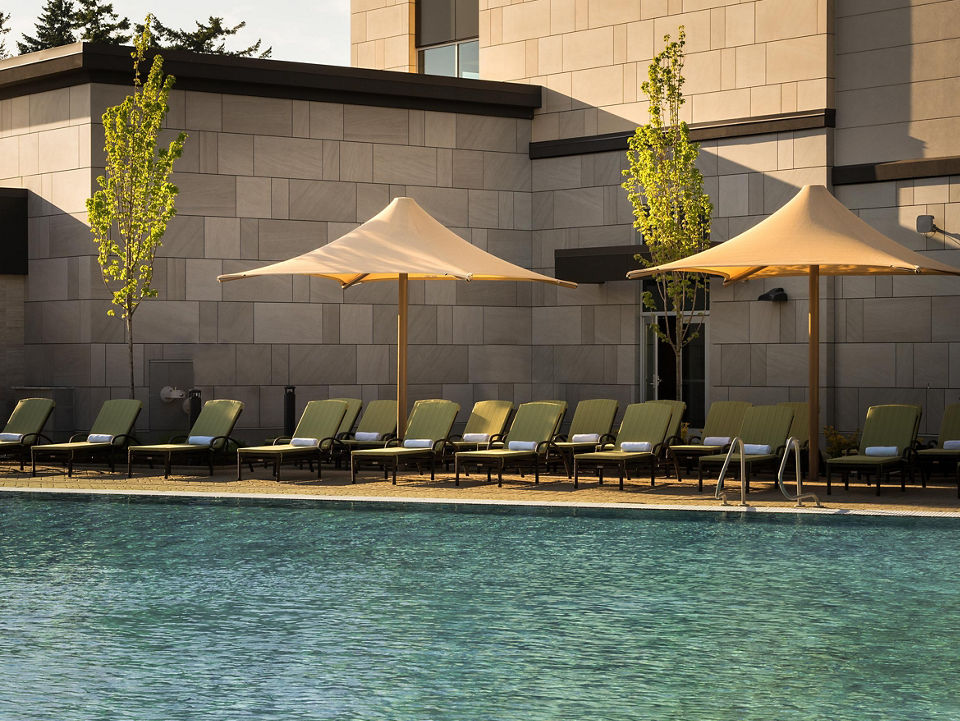 Pool lounge chairs uniformly placed next to an outdoor swimming pool