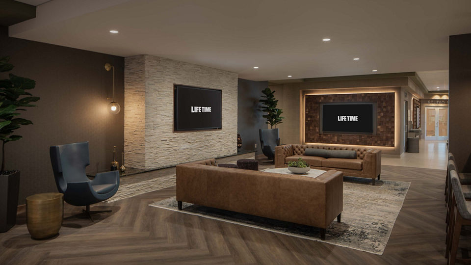 Open seating area with couches and televisions at Life Time