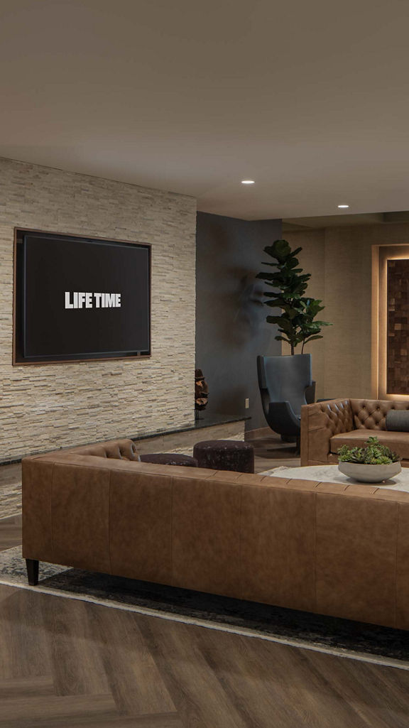 Open seating area with couches and televisions at Life Time