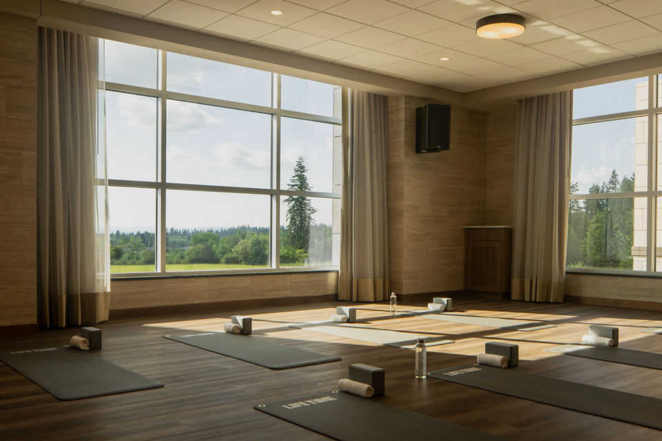 a calming yoga studio with large windows, yoga mats, towels, yoga blocks, and water bottles