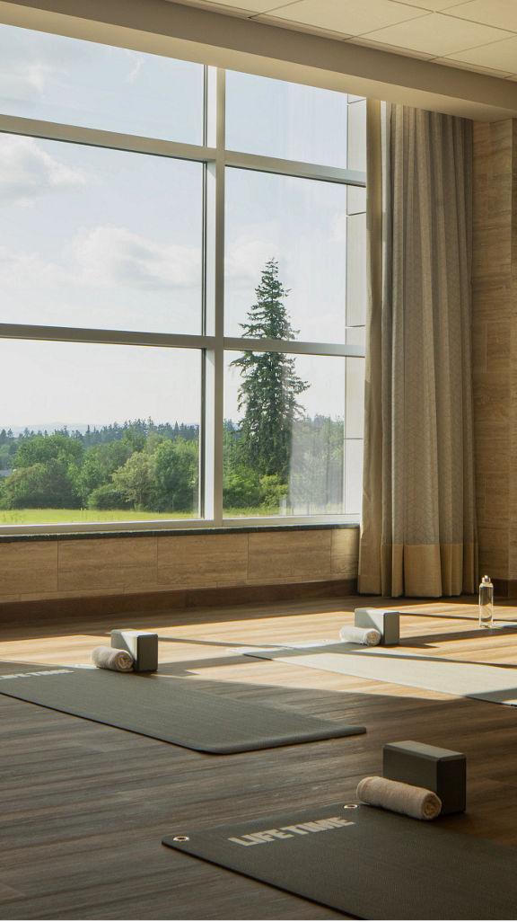 a calming yoga studio with large windows, yoga mats, towels, yoga blocks, and water bottles