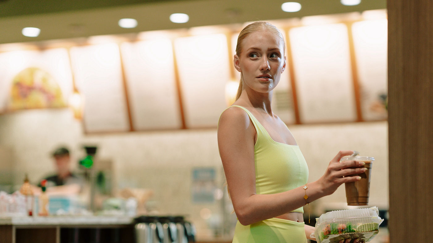 A member carrying a to-go salad and smoothie in a Life Time LifeCafe