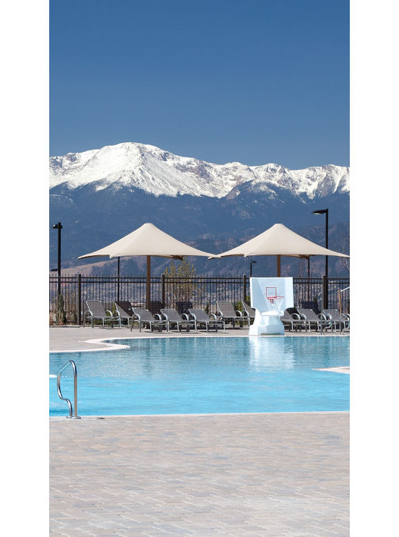 An outdoor pool with waterslides, and mountains in the background