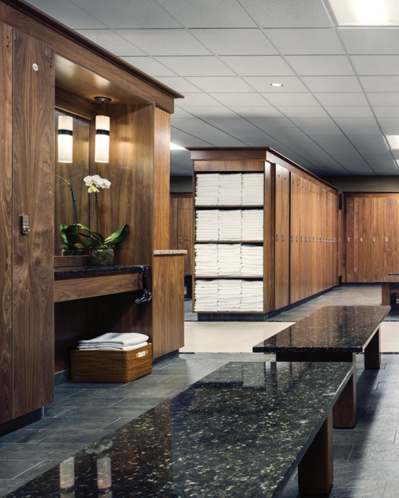 An upscale locker room with rows of wooden lockers and shelves of white towels