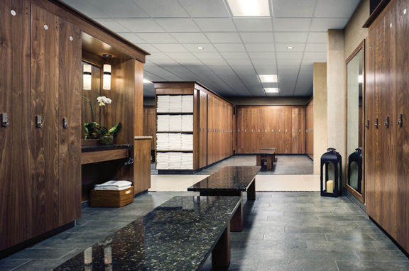 An upscale locker room with rows of wooden lockers and shelves of white towels