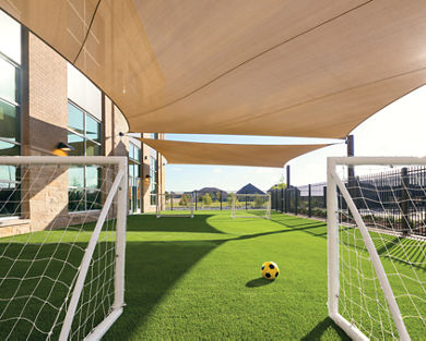 Two soccer goals stand next to each other with a soccer ball in between on an outdoor turf field