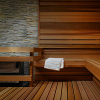 Inside a large sauna with wood paneling and a while towel draped over the bench