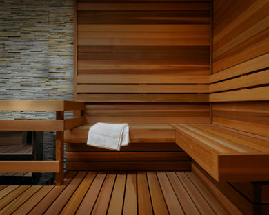 Inside a large sauna with wood paneling and a while towel draped over the bench