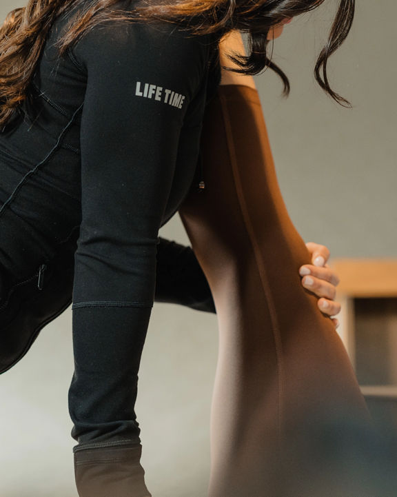 A Life Time Personal Trainer stretching a member's leg during a dynamic stretch session