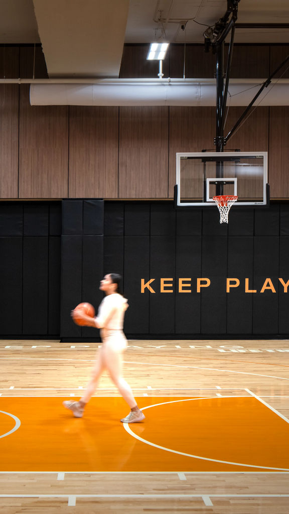 A woman holding a basketball walking towards a basketball hoop