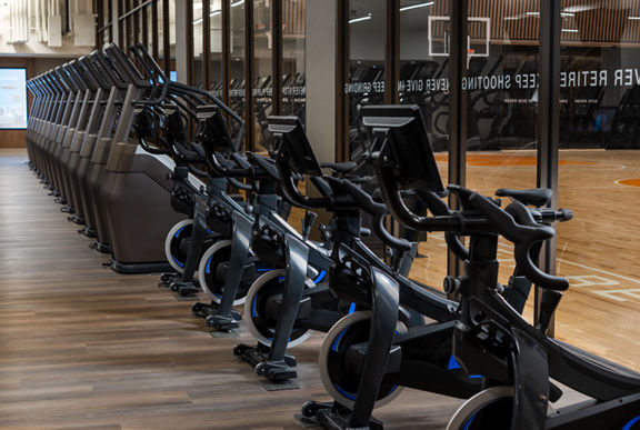 Stationary bikes and stairclimbers on the fitness floor at the Life Time Dumbo club location