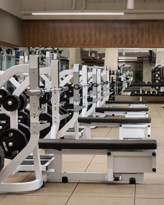 Weight benches and free weights on the fitness floor at Life Time