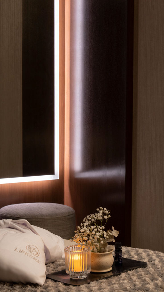 Serene massage room with a LifeSpa robe, candle and flowers atop a massage table