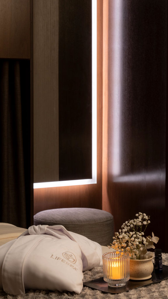 Serene massage room with a LifeSpa robe, candle and flowers atop a massage table