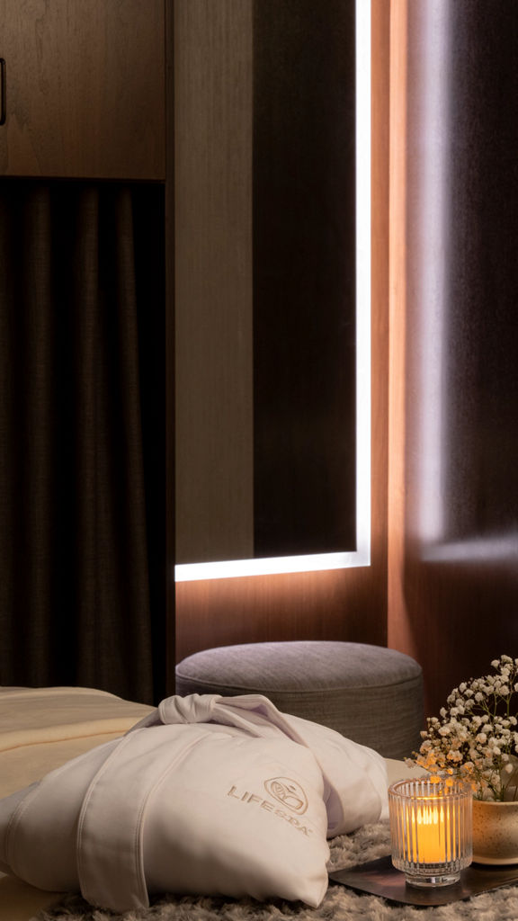 Serene massage room with a LifeSpa robe, candle and flowers atop a massage table