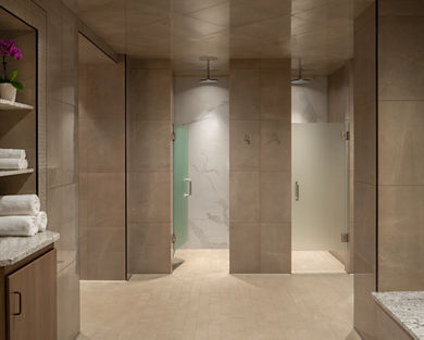 a shower area with glass doored shower stalls and stacks of fresh towels