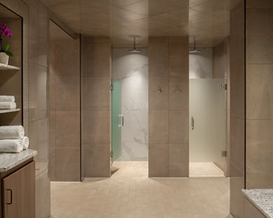 a shower area with glass doored shower stalls and stacks of fresh towels